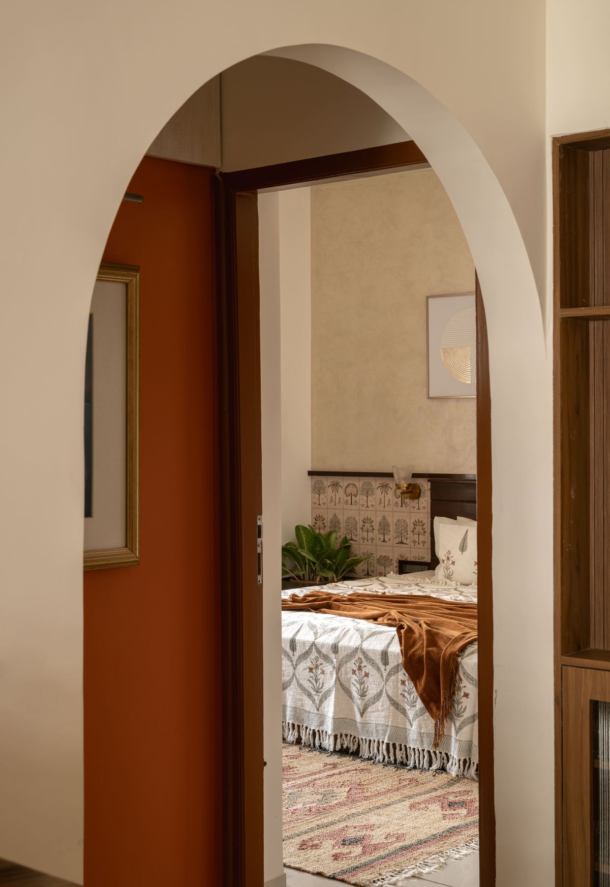 Arched doorway opening into a bedroom with a terracotta wall