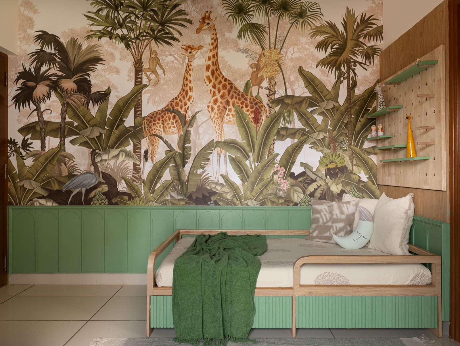 Jungle mural with giraffes above a sage green arched daybed